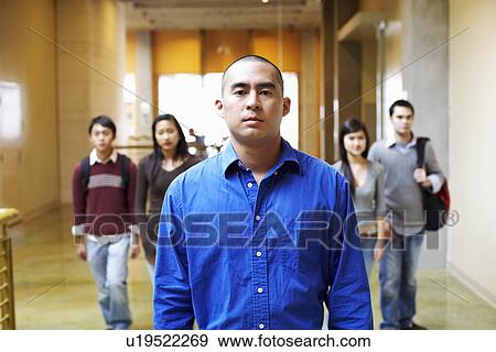 Portrait of a young man walking in the corridor with four people behind him View Large Photo Image Stock Photo - Portrait of a young man walking in the corridor with four people behind him. Fotosearch