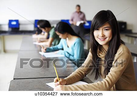 Portrait of a young woman giving exams in a classroom and smiling View Large Photo Image Stock Photo - Portrait of a young woman giving exams in a classroom and smiling. Fotosearch