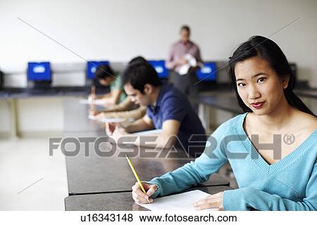 Stock Photo - Portrait of a young woman giving exams in a classroom. Fotosearch
