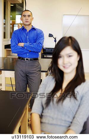Portrait of a young woman grinning with a young man standing behind her View Large Photo Image Stock Image - Portrait of a young woman grinning with a young man standing behind her. Fotosearch