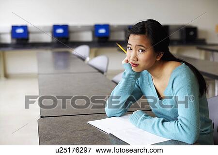 Stock Photo - Portrait of a young woman sitting in an examination room with her hand on her chin. Fotosearch