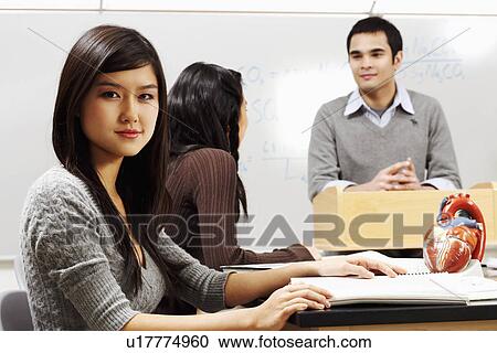 Portrait of a young woman sitting with her friend in the classroom View Large Photo Image Stock Image - Portrait of a young woman sitting with her friend in the classroom. Fotosearch