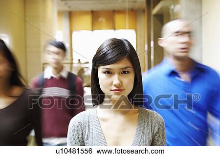 Portrait of a young woman walking in the corridor with three people behind her View Large Photo Image Stock Photograph - Portrait of a young woman walking in the corridor with three people behind her. Fotosearch