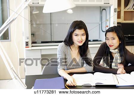 Portrait of two young women studying at a table and grinning View Large Photo Image Stock Image - Portrait of two young women studying at a table and grinning. Fotosearch