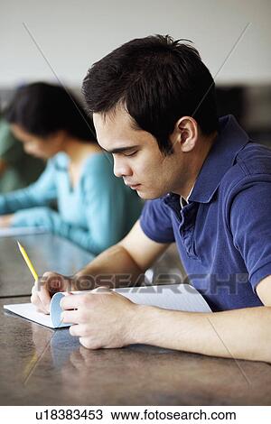 Side profile of a young man giving exams in a classroom View Large Photo Image Stock Image - Side profile of a young man giving exams in a classroom. Fotosearch
