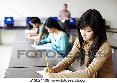Side profile of a young woman giving exams in a classroom View Large Photo Image Stock Photo - Side profile of a young woman giving exams in a classroom. Fotosearch
