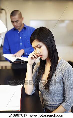Side profile of a young woman contemplating with a young man standing behind her View Large Photo Image Stock Photo - Side profile of a young woman contemplating with a young man standing behind her. Fotosearch