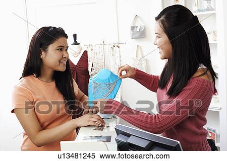 Close-up of a young woman showing a necklace to a woman View Large Photo Image Stock Photography - Close-up of a young woman showing a necklace to a woman. Fotosearch