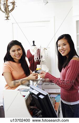 Stock Image - Portrait of a young woman paying with a credit card. Fotosearch