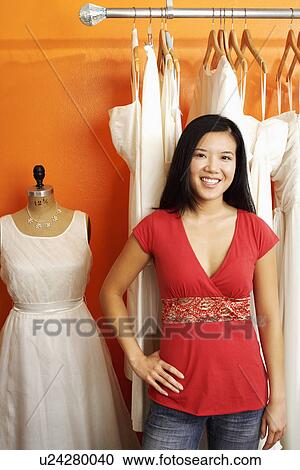 Portrait of a young woman standing in a clothing store View Large Photo Image Stock Image - Portrait of a young woman standing in a clothing store. Fotosearch