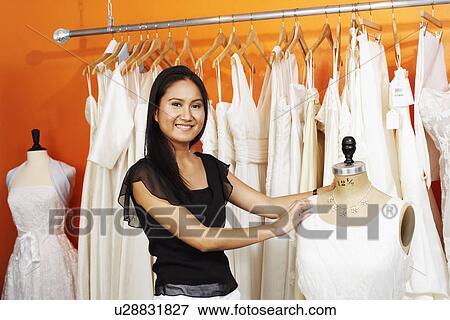Stock Photo - Portrait of a young woman standing with a mannequin in a clothing store. Fotosearch