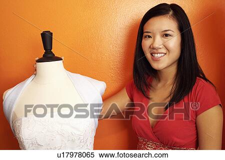 Portrait of a young woman standing with her arm around a mannequin View Large Photo Image Stock Photography - Portrait of a young woman standing with her arm around a mannequin. Fotosearch