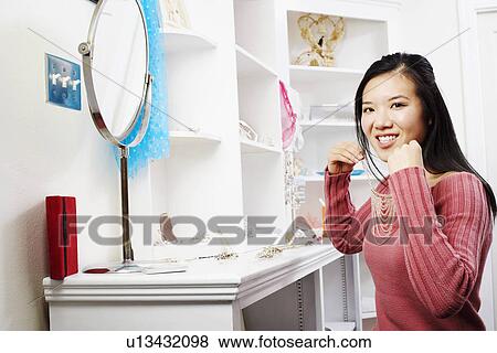 Portrait of a young woman trying on a necklace in a store View Large Photo Image Stock Photo - Portrait of a young woman trying on a necklace in a store. Fotosearch