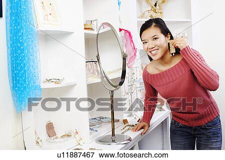 Stock Photo - Portrait of a young woman trying on an earring in a store. Fotosearch
