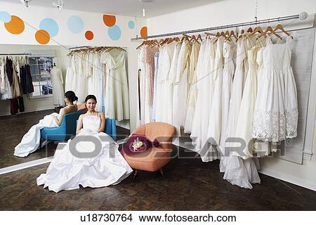 Portrait of a young woman wearing a wedding dress and sitting in a bridal store View Large Photo Image Picture - Portrait of a young woman wearing a wedding dress and sitting in a bridal store. Fotosearch