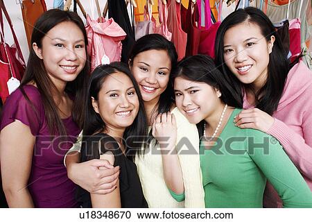 Stock Image - Portrait of five young women standing in a clothing store. Fotosearch