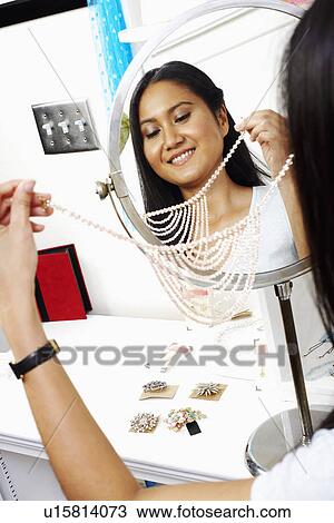 Reflection of a young woman trying on a necklace in a store View Large Photo Image Stock Image - Reflection of a young woman trying on a necklace in a store. Fotosearch
