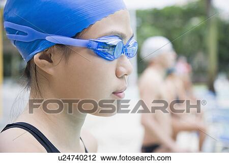 Close-up of a young woman wearing swimming goggles and standing at a poolside View Large Photo Image Stock Image - Close-up of a young woman wearing swimming goggles and standing at a poolside. Fotosearch