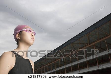 Low angle view of a young woman wearing swimming goggles View Large Photo Image Stock Image - Low angle view of a young woman wearing swimming goggles. Fotosearch