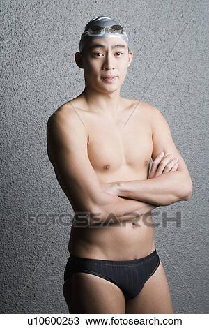 Portrait of a young man standing with his arms crossed View Large Photo Image Stock Image - Portrait of a young man standing with his arms crossed. Fotosearch
