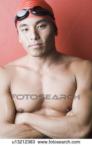 Stock Image - Portrait of a young man standing with his arms crossed. Fotosearch