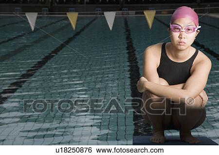 Portrait of a young woman squatting on a starting block View Large Photo Image Stock Photograph - Portrait of a young woman squatting on a starting block. Fotosearch