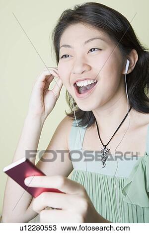 Close-up of a young woman listening to music and laughing View Large Photo Image Stock Image - Close-up of a young woman listening to music and laughing. Fotosearch