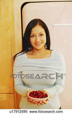 Portrait of a young woman holding a bowl of cherries View Large Photo Image Stock Photography - Portrait of a young woman holding a bowl of cherries. Fotosearch