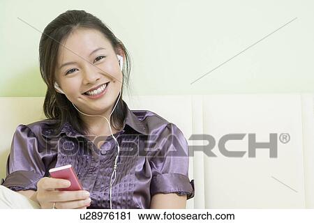Portrait of a young woman listening to music and smiling View Large Photo Image Stock Image - Portrait of a young woman listening to music and smiling. Fotosearch