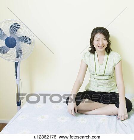 Portrait of a young woman sitting cross-legged on the bed View Large Photo Image Stock Photograph - Portrait of a young woman sitting cross-legged on the bed. Fotosearch