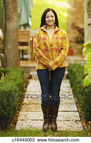 Portrait of a young woman smiling and standing with her hands clasped View Large Photo Image Stock Image - Portrait of a young woman smiling and standing with her hands clasped. Fotosearch