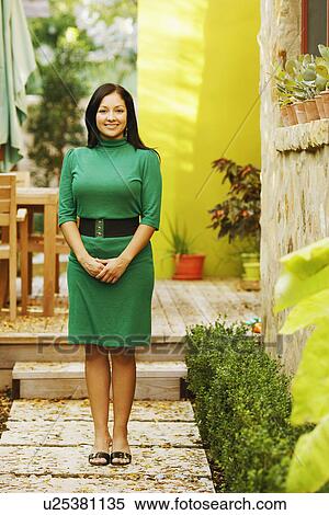 Portrait of a young woman smiling and standing with her hands clasped View Large Photo Image Stock Photography - Portrait of a young woman smiling and standing with her hands clasped. Fotosearch