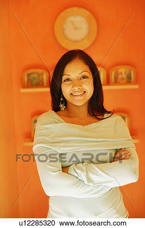 Portrait of a young woman standing with her arms crossed and smiling View Large Photo Image Stock Image - Portrait of a young woman standing with her arms crossed and smiling. Fotosearch