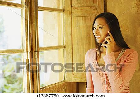 Portrait of a young woman using a mobile phone and smiling View Large Photo Image Stock Image - Portrait of a young woman using a mobile phone and smiling. Fotosearch