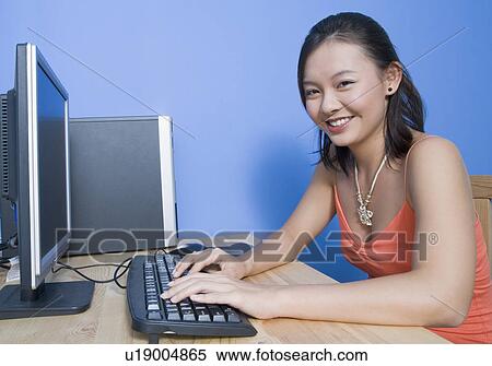 Portrait of a young woman using a computer and smiling View Large Photo Image Stock Photography - Portrait of a young woman using a computer and smiling. Fotosearch