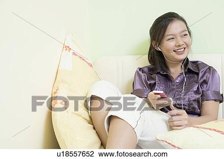 Young woman leaning against a wall and listening to music View Large Photo Image Stock Image - Young woman leaning against a wall and listening to music. Fotosearch
