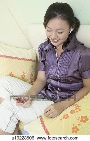 Young woman listening to music and smiling View Large Photo Image Stock Photograph - Young woman listening to music and smiling. Fotosearch
