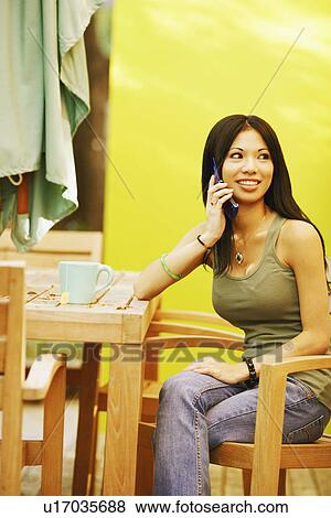 Young woman sitting in an armchair and using a mobile phone View Large Photo Image Stock Photo - Young woman sitting in an armchair and using a mobile phone. Fotosearch