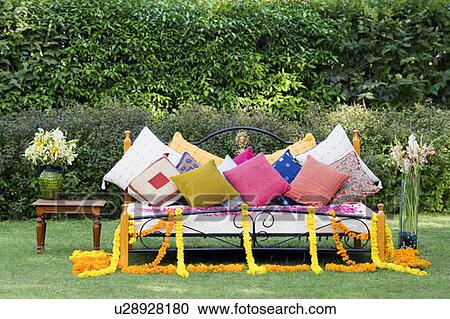 Stock Image - Bed with cushions and vases on a lawn. Fotosearch