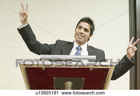 Businessman showing peace signs at a lectern View Large Photo Image Stock Image - Businessman showing peace signs at a lectern. Fotosearch