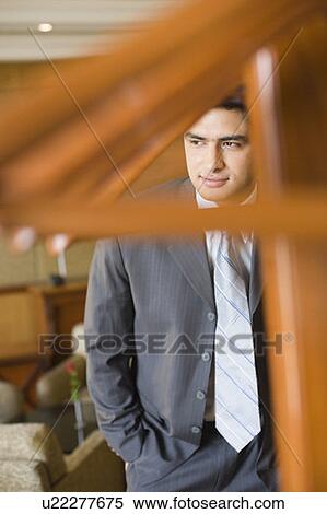 Stock Photography - Businessman standing with his hands in his pockets and smirking. Fotosearch