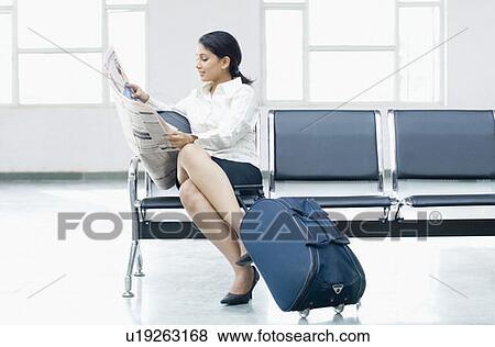 Businesswoman sitting on a chair at an airport and reading a newspaper View Large Photo Image Stock Photo - Businesswoman sitting on a chair at an airport and reading a newspaper. Fotosearch