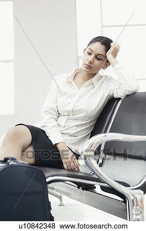 Stock Photo - Businesswoman sitting on a chair with her head in her hand. Fotosearch