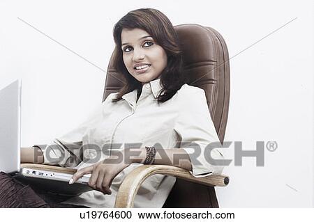 Close-up of a businesswoman with a laptop on her lap sitting on an office chair View Large Photo Image Stock Image - Close-up of a businesswoman with a laptop on her lap sitting on an office chair. Fotosearch
