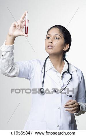 Stock Photo - Close-up of a female doctor looking at a test tube of blood sample. Fotosearch