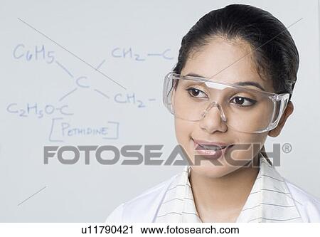 Stock Image - Close-up of a female lab technician wearing a protective eyewear. Fotosearch