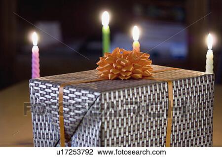 Stock Image - Close-up of a gift with burning candles. Fotosearch