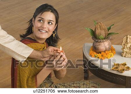 Stock Photography - Close-up of a man's hand giving an oil lamp to a young woman. Fotosearch