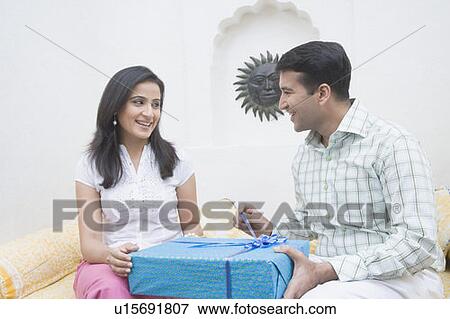 Close-up of a mid adult man giving a gift to a mid adult woman and smiling View Large Photo Image Stock Photo - Close-up of a mid adult man giving a gift to a mid adult woman and smiling. Fotosearch