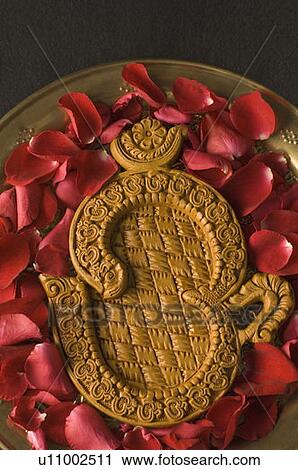 Stock Image - Close-up of a ohm symbol with rose petals in a plate. Fotosearch
